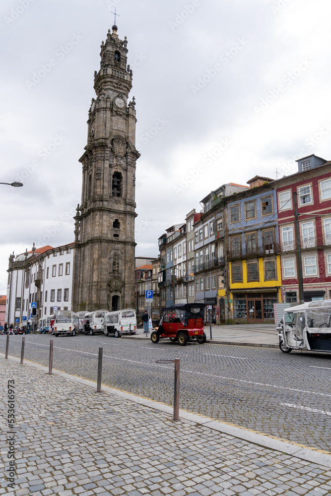 Obraz premium Tower of the Clérigos Church in Porto, seen from across the street, with parked tourist cars.