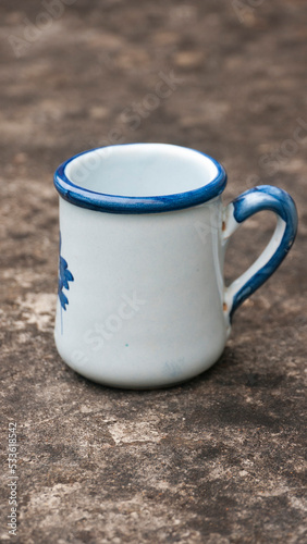 Taza de porcelana blanca con adornos azules sobre mesa de piedra oscura