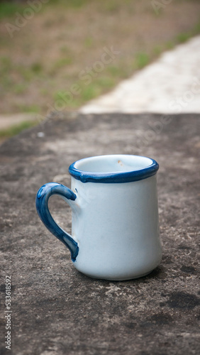 Taza de porcelana blanca con adornos azules sobre mesa de piedra oscura