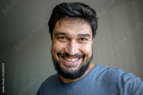Fotografia Portrait of a brunette man with gray hair and a beard, smiling at home