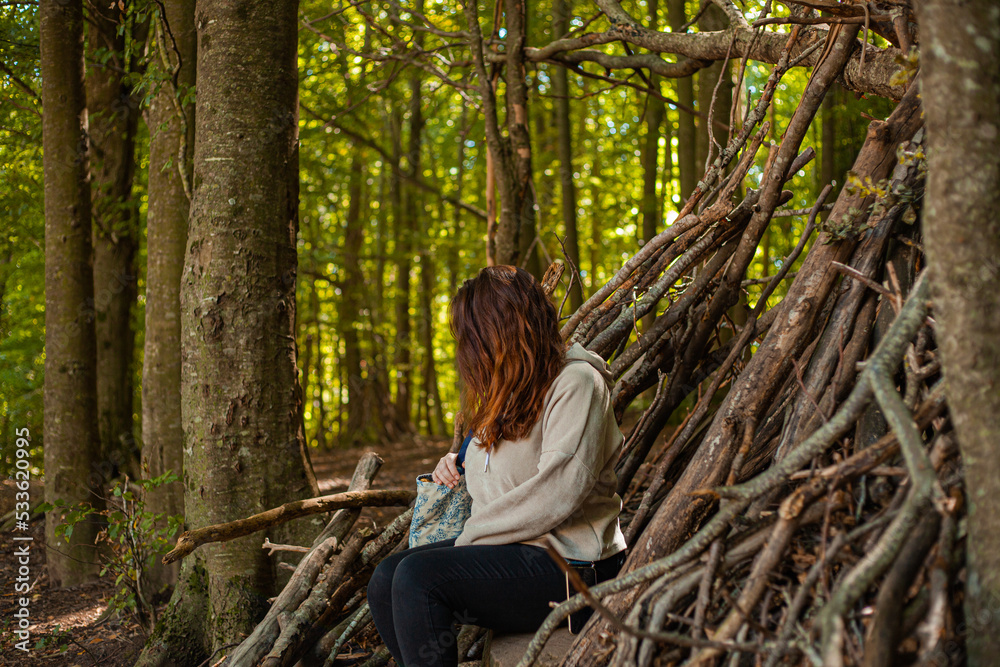 red-haired girl sitting in the doorway of a cabin in the woods without showing her face red-haired girl sitting in the doorway of a cabin in the woods without showing her face