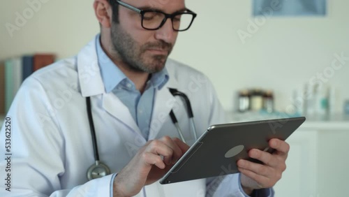 Caucasian doctor in glasses in surgeon coat on digital tablet capturing medical data. Social network. Telemedicine, Remote. Distance consultation. remote healthcare services. 4k footage