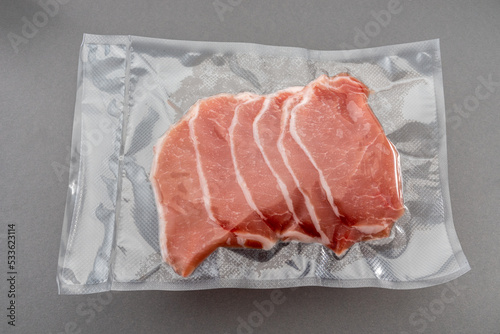 Pork loin slices in vacuum packed sealed for sous vide cooking isolated on gray background