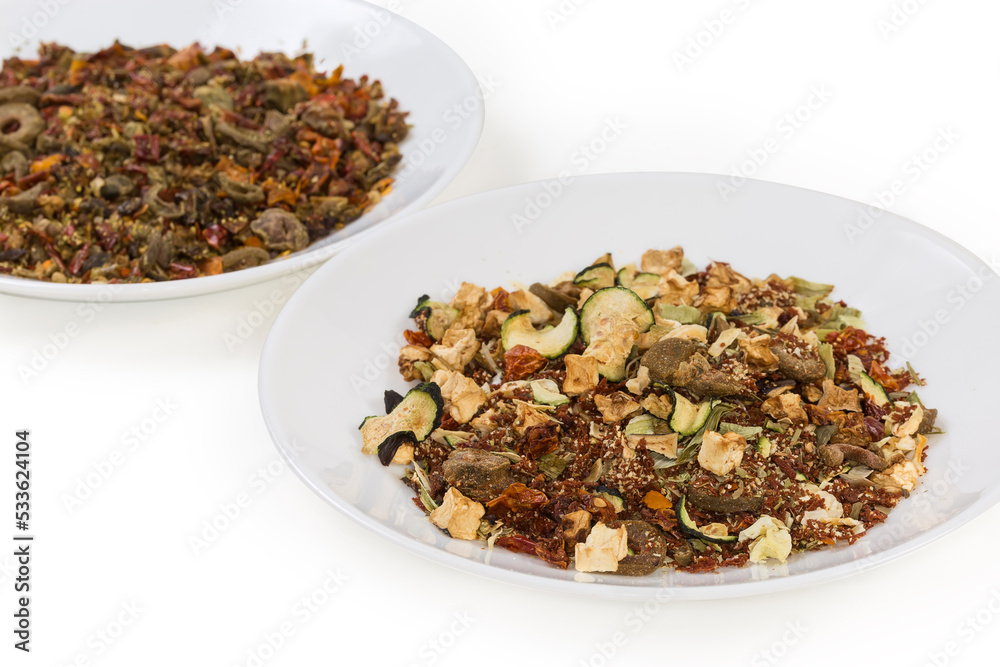 Two mixtures of spices and dried vegetables on two dishes Two mixtures of spices and dried vegetables on two dishes