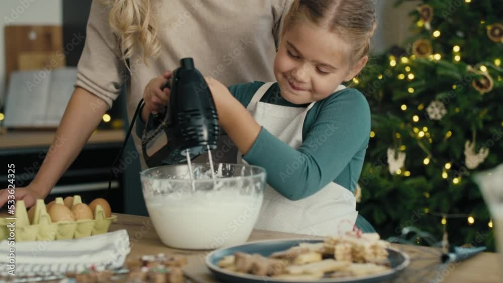 Caucasian mother and daughter preparing baking using electric mixer in the kitchen before Christmas. Shot with RED helium camera in 8K.   