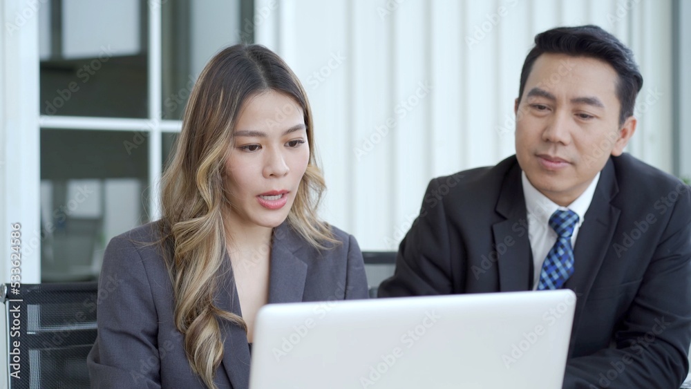 Asian businessman and businesswoman talking together in an office Asian businessman and businesswoman talking together in an office