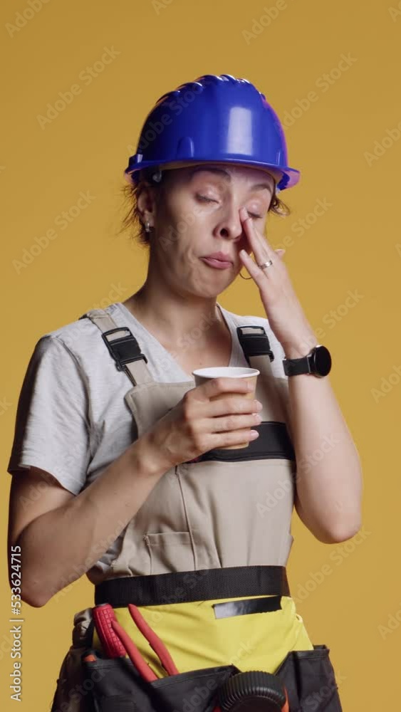 Vertical video: Portrait of sleepy handywoman drinking coffee cup at building work, feeling exhausted and falling asleep. Construction worker serving espresso refreshment and beverage over yellow Vertical video: Portrait of sleepy handywoman drinking coffee cup at building work, feeling exhausted and falling asleep. Construction worker serving espresso refreshment and beverage over yellow