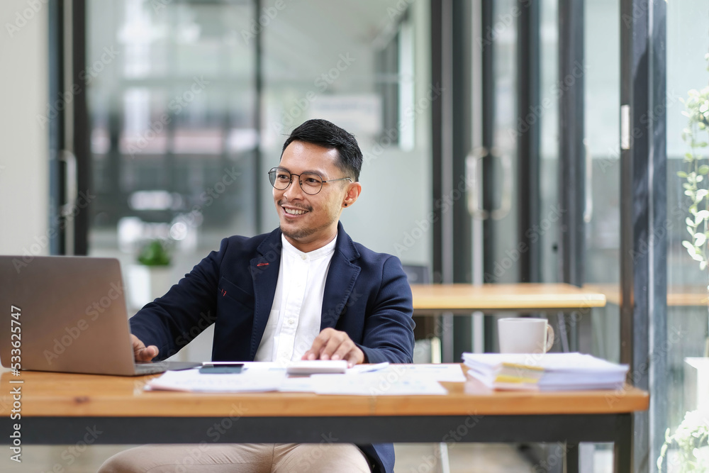 Fototapeta premium Successful and professional adult Asian businessman or male boss in formal suit working at his office desk.