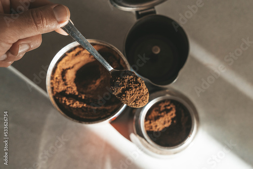 Fototapeta Naklejka Na Ścianę i Meble -  Metal coffee maker for brewing espresso on the stove. Teaspoon with ground coffee beans