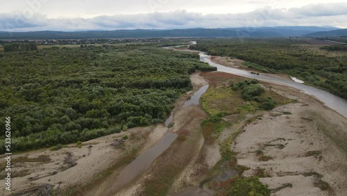 Aerial view on the wide Stryi river among woodlands, drone shot forward panning down photo