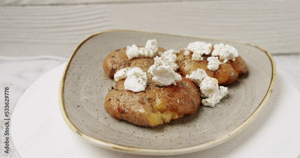Freshly baked potatoes with cheese feta rotating on white plate. Delicious food. Top view. Close up. Concept Restaurant Grilled food. Organic and Tasty. Gastronomy Cafe. Freshly baked potatoes with cheese feta rotating on white plate. Delicious food. Top view. Close up. Concept Restaurant Grilled food. Organic and Tasty. Gastronomy Cafe.