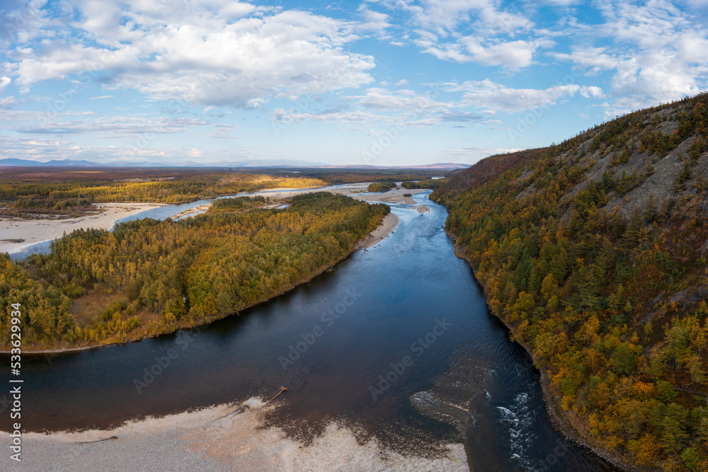 Aerial view of the river. Top view of the river bed and hills. Forest on the river bank. Picturesque autumn landscape. Beautiful nature of Siberia. Ola River, Magadan Region, Far East of Russia.