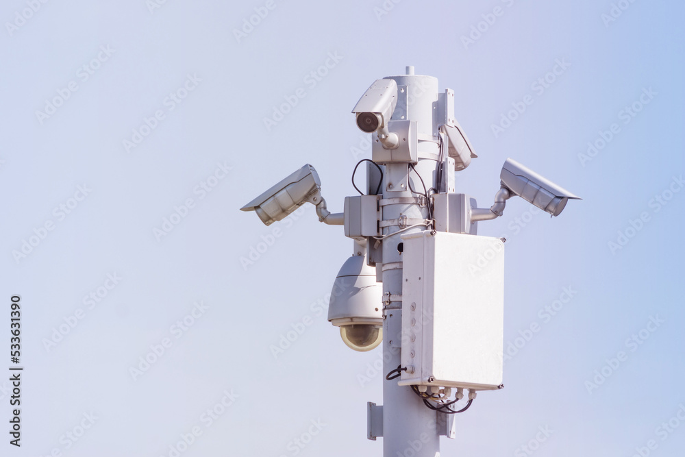 Public security cameras, capture the townspeople. White cameras are mounted on a metal pole. Public security cameras, capture the townspeople. White cameras are mounted on a metal pole.