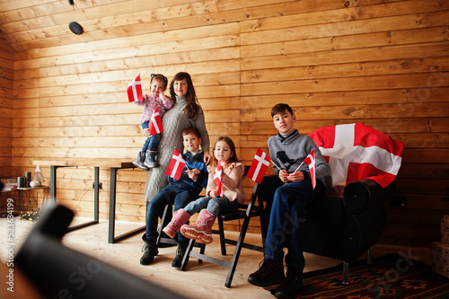 Fototapeta Naklejka Na Ścianę i Meble -  Family with Denmark flags inside wooden house. Travel to Scandinavian countries. Happiest danish people's .