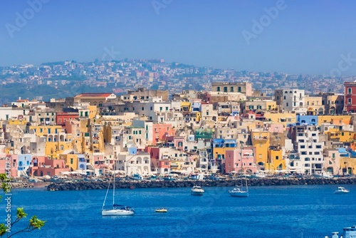 Procida in sunny summer day. Colorful houses, cafes and restaurants, fishing boats and yachts in Marina Corricella, blue sky and azure sea, Procida Island, Italy. © IgorZh