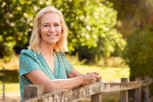 Portrait Of Casually Dressed Mature Or Senior Woman Leaning On Fence On Walk In Countryside © Monkey Business