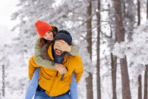 Couple on winter vacation  boyfriend piggybacking girlfriend on snowy winter day