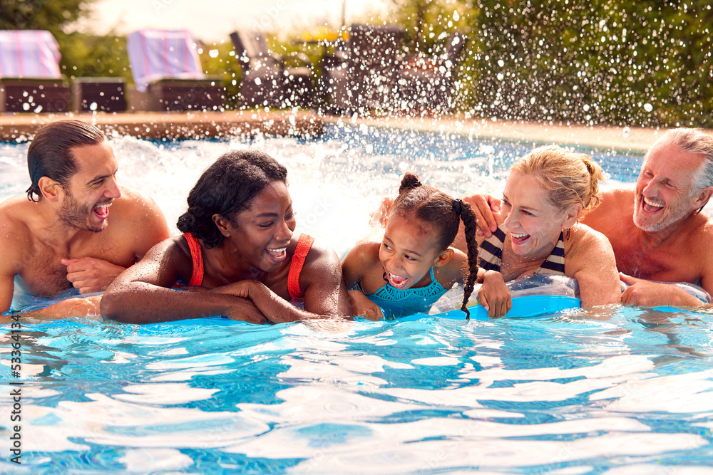 Smiling Multi-Generation Family On Summer Holiday Relaxing In Swimming Pool On Airbed Smiling Multi-Generation Family On Summer Holiday Relaxing In Swimming Pool On Airbed