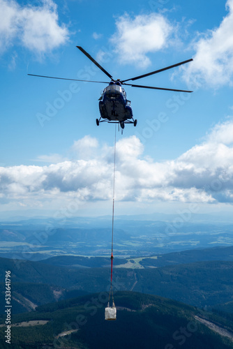 Helicopter carrying heavy cargo in moutain landscape