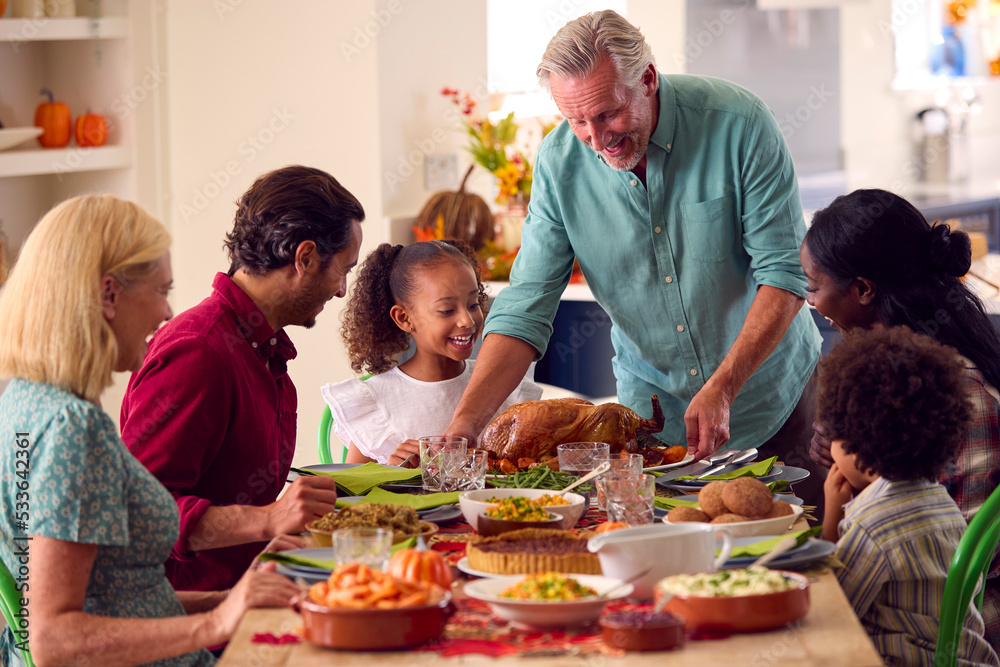 Grandfather Serving As Multi-Generation Family Celebrating Thanksgiving At Home Eating Meal Together