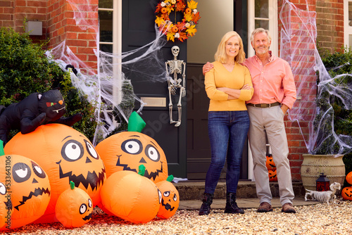 Portrait Of Grandparents At Home Putting Up Halloween Decorations For Trick Or Treat