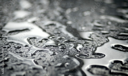 Close-up of waterdrops on silver surface. Horizontal image with selective focus.