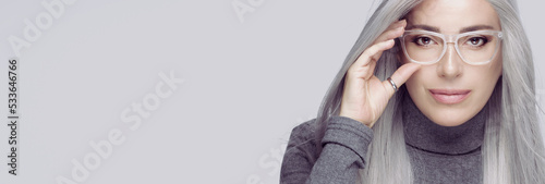 Konstfotografi successful business woman with long silver hair, wearing fashionable clear eyeglasses staring at camera with confidence