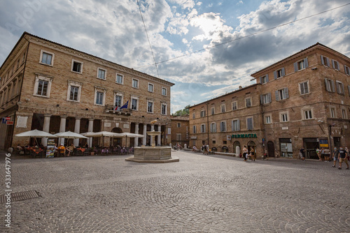 Urbino, Marche, Italy - July 2021: central historical square with medieval buildings and open air cafe in the city of Urbino, Marche, Italy.