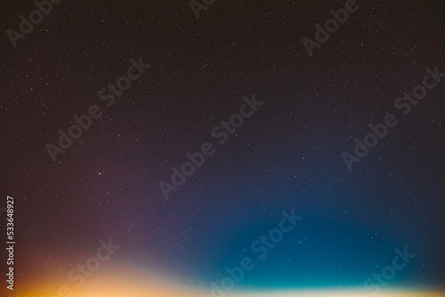 Real night sky stars background with natural colourful sky gradient. Sunset, sunrise light and starry sky. Yellow and blue colors over horizon. Nature background.
