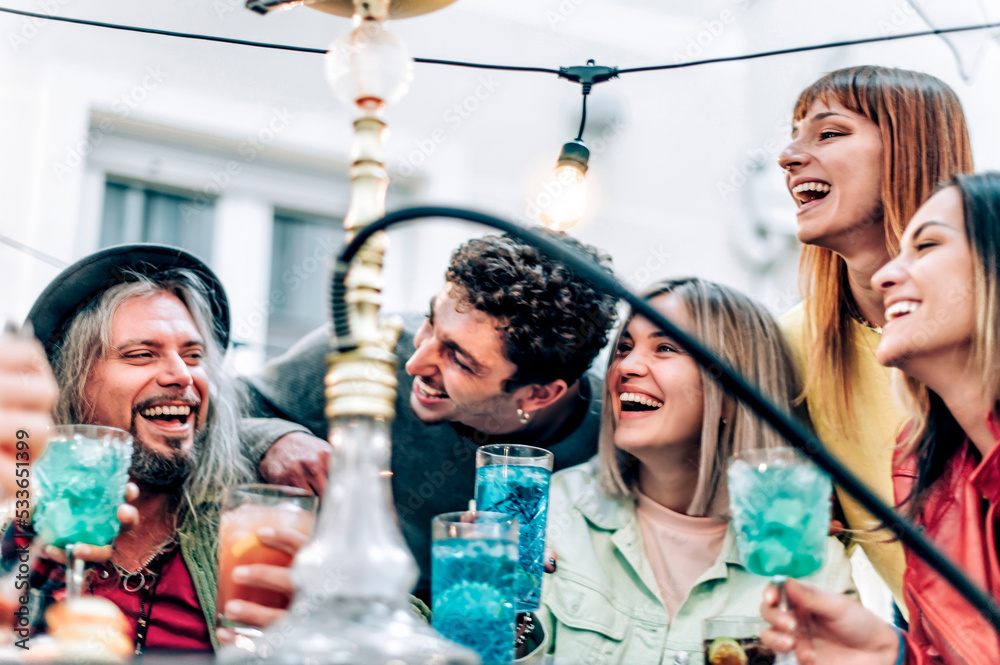 Happy multiracial group of friends drinking cocktail and smoking shisha