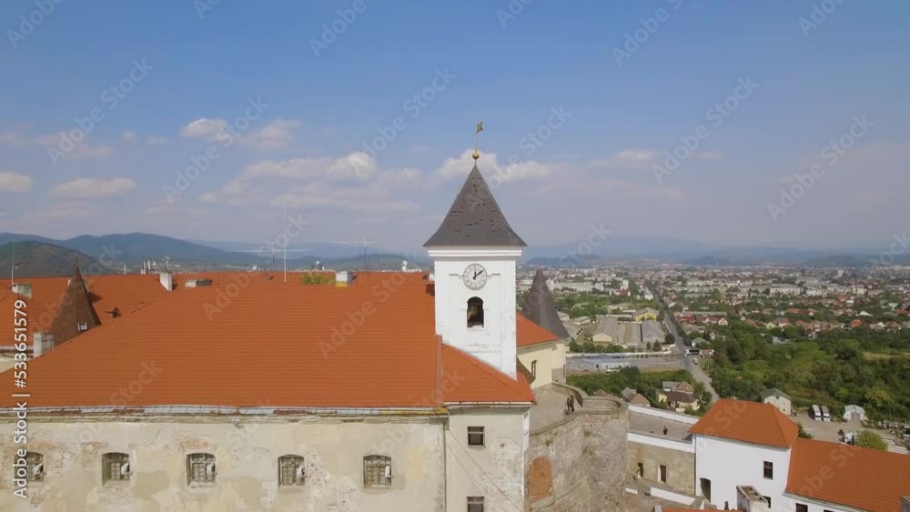 Drone flies over clock tower in medieval castle on the hill in small euro city Drone flies over clock tower in medieval castle on the hill in small euro city