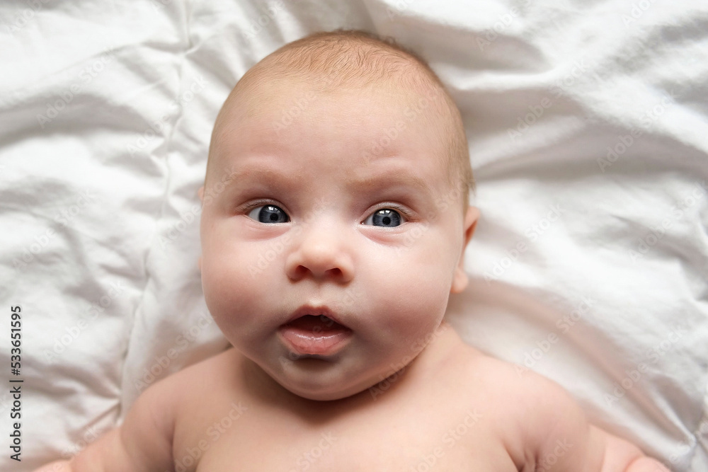 Closeup portrait of Newborn baby on white blanket. Soft focus. Infant is lying, yawning. One, two week age. Infant girl waking up on bed at home. New life and growing up concept. Real People. Closeup portrait of Newborn baby on white blanket. Soft focus. Infant is lying, yawning. One, two week age. Infant girl waking up on bed at home. New life and growing up concept. Real People.