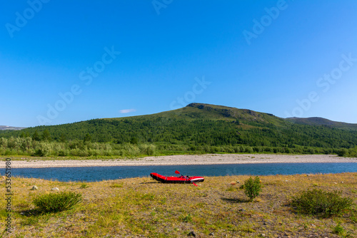 A light inflatable boat packfaft lies on the bank of the river. Rafting on the northern river.