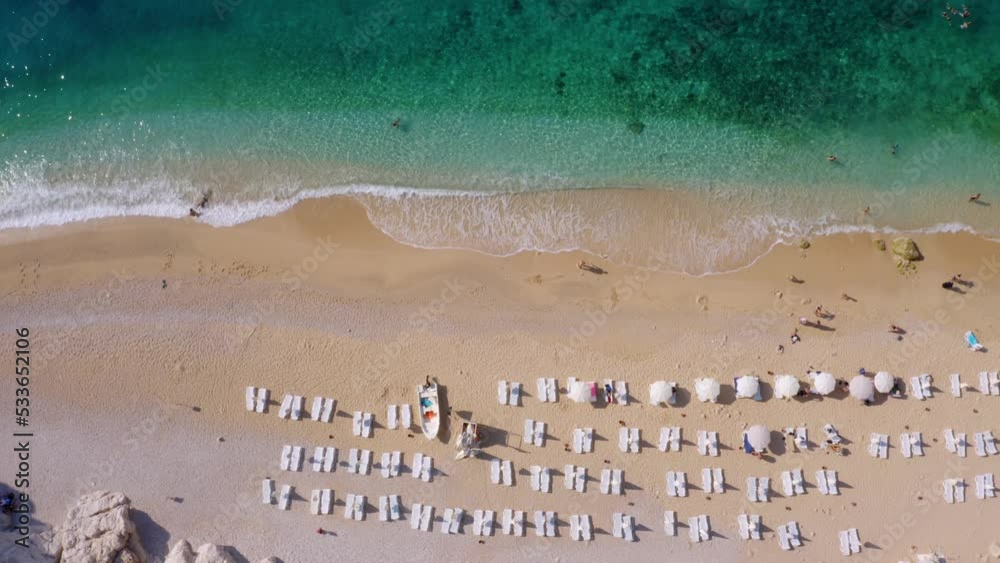 Top view tourists enjoying vacation on sandy beach of tropical island. Turquoise ocean waves on coastline. Top view tourists enjoying vacation on sandy beach of tropical island. Turquoise ocean waves on coastline.