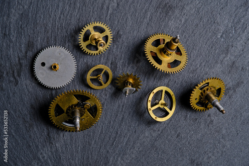 Old metall gears from mechanical watches slate stone background. © freeman83