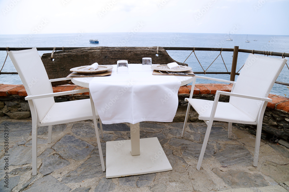 A set table on a terrace with a view of the sea.