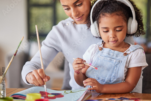 Mother, girl and bonding in painting activity with music headphones, radio or audio for autism help. Brazilian woman, art parent and creative child listening to relax autism podcast in house or home photo