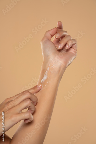 Close up cropped woman apply hand perfect skin hand cream isolated on beige studio background.