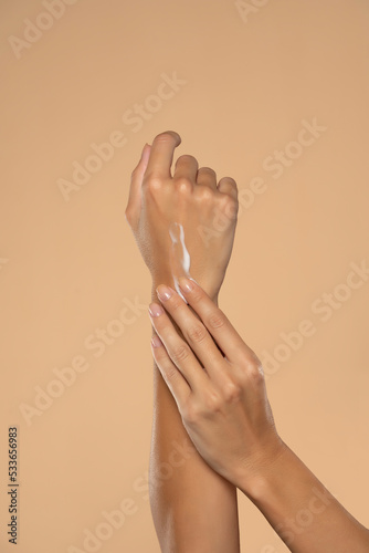 Close up cropped woman apply  hand perfect skin hand cream isolated on beige studio  background.