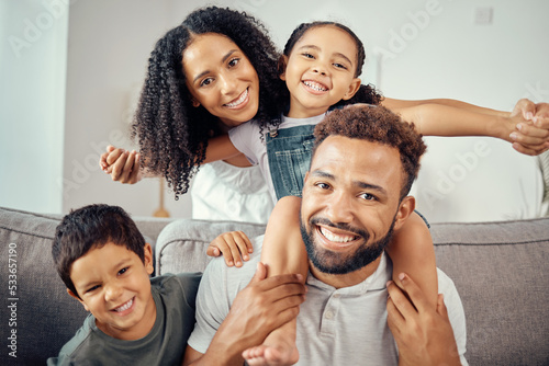 Mom, dad and kids, a happy family on a sofa in living room at home. Mother, father and children smile, sitting on couch together. Portrait of a man and woman with smiling kids, a celebration of love © David L/peopleimages.com