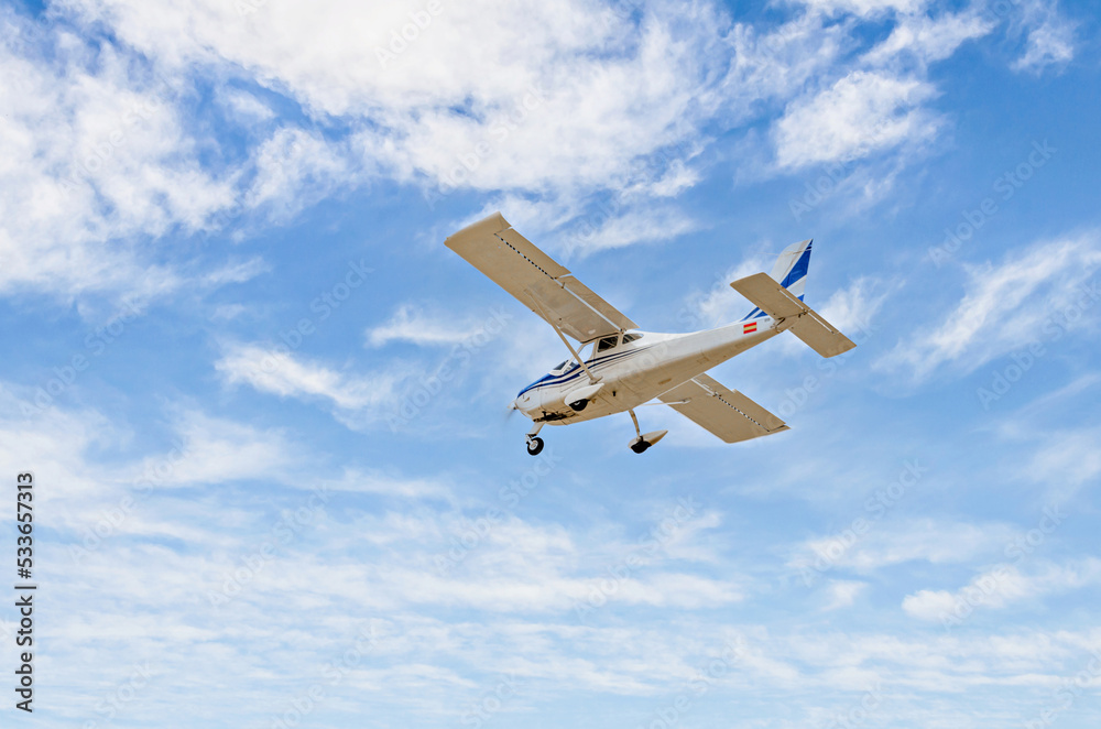 Fototapeta premium Single engine ultralight plane flying in the blue sky with white clouds