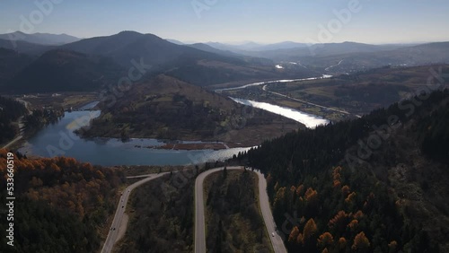 Aerial view of the Carpathian landscape with serpent road and river Stryi among mountains in early autumn, drone slowly flies backwards photo