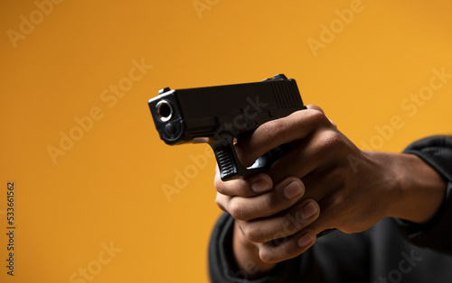 Close-up of hands holding a gun isolated on yellow background.