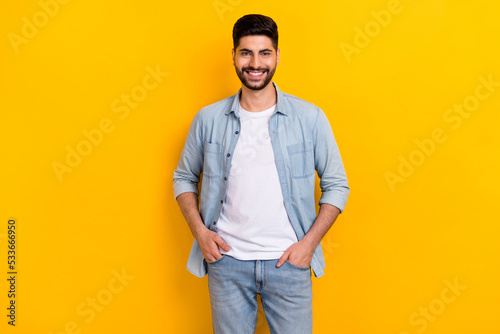 Photo of young positive guy confidently looking camera sure best worker hands pockets isolated on yellow color background © deagreez