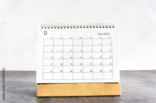 September 2023 Desktop calendar for planners and reminders on a wooden table on a white background.