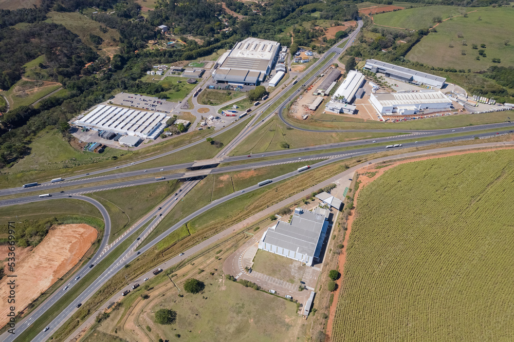 Aerial view of the Dom Pedro Highway at the height of the city of Itatiba. Industries, cars on the highway and vegetation on the side of the road. Aerial view of the Dom Pedro Highway at the height of the city of Itatiba. Industries, cars on the highway and vegetation on the side of the road.