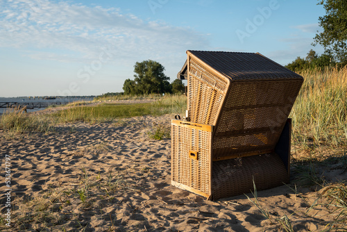 Beach chair at Harriersand Beach, Schwanewede Germany. Relaxing  under blue sky, warm sand, green grass and trees along Weser river. photo