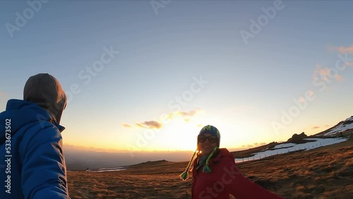 A couple hiking in cold winter during sunrise at Ladinger Spitz in the Saualpe mountain range, Lavantal Alps, Carinthia, Austria, Europe. Man filming with action camera. Romantic leisure activities photo