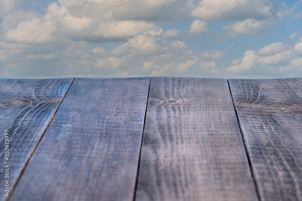 Empty wooden table and beautiful blue sky and white clouds in background. Perspective brown wooden board