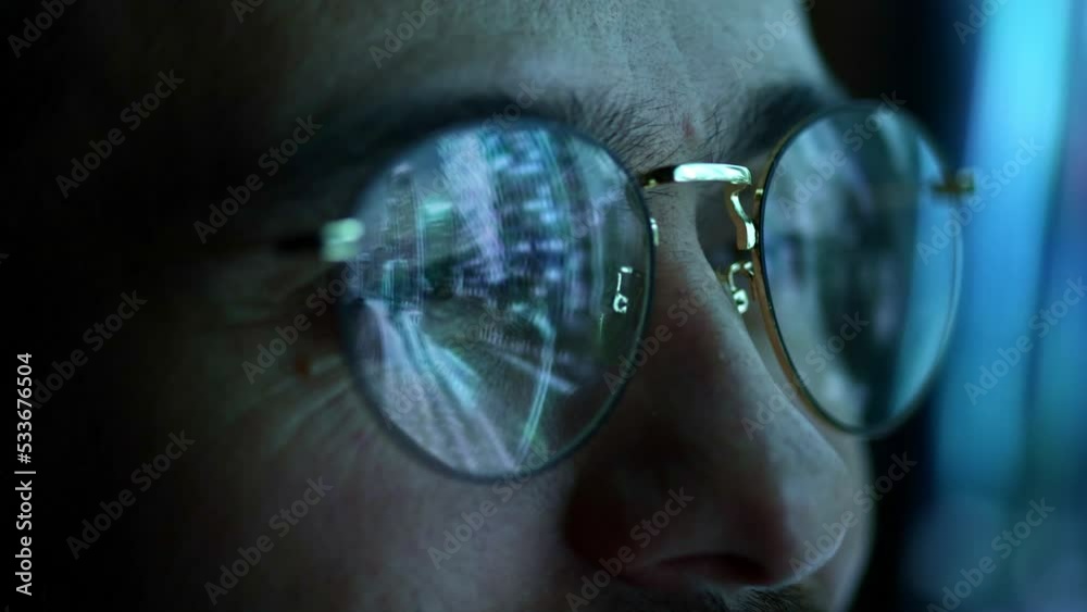 Close up view of man's eyes in eyewear looking at pc screen with computer reflection at eyeglasses. Using internet, working online, tracking database.